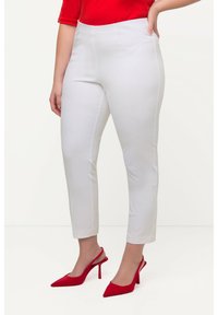 Witte, slim-fit, enkellange broeken met een gladde textuur en subtiele stikseldetails, gecombineerd met rode, puntige hoge hakken.
