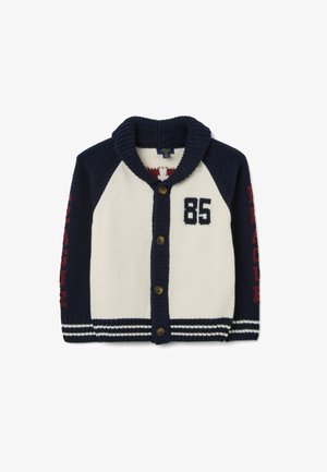 Cardigan en tricot bleu marine et crème avec col châle, cinq boutons marron, impression "85" sur la poitrine et texte rouge sur les manches avec un ourlet rayé.
