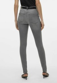 Jeans ajustados grises con un diseño ceñido, que cuentan con bolsillos traseros y costuras en contraste, combinados con zapatos negros.