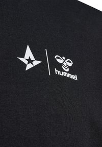 Svart t-shirt med en vit stjärnlogotyp och Hummel-bilogo. Materialet verkar vara slätt med en enkel rund halsringning och korta ärmar.