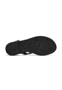 Suola nera di scarpa con superficie in gomma testurizzata, caratterizzata da intricati motivi a spirale e un bordo liscio.