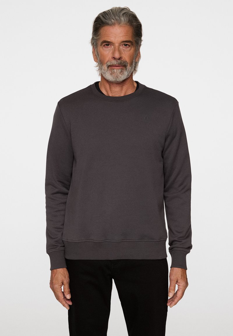 Sweatshirt gris en tissu doux, avec un col rond, des manches longues et des poignets et un ourlet côtelés. Design simple avec un minimum de branding.