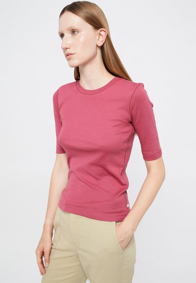 Rövid ujjú rózsaszín póló rugalmas pamutból, karcsúsított szabású, kerek nyakkal, finom varrással és kis logó címkével az alsó szegélyen.