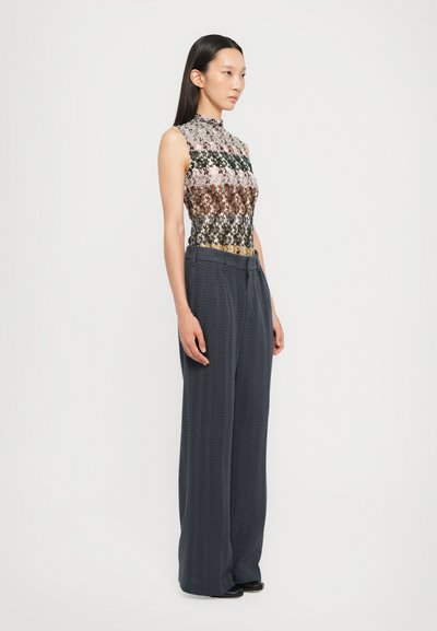Top fără mâneci cu un design din dantelă florală multicoloră; asortat cu pantaloni largi cu model, creând un contrast textural în straturi.