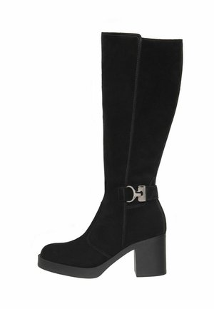 Bottes noires en daim montantes avec un talon bloc, présentant un accent en métal argenté et des coutures contrastantes sur le côté.