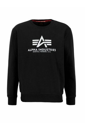 Melnā sporta krekls ar apaļu kakla izgriezumu, centrā ar baltu grafisku logo un tekstu "Alpha Industries Knoxville, Tennessee, U.S.A.".