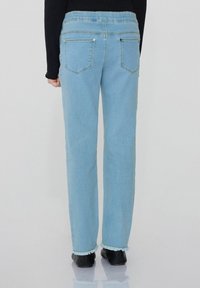 Světle modré džíny s uvolněným střihem, třepícími se lemy a standardními zadními kapsami. Mají jednoduchý design pasu a stříbrné kovové detaily.