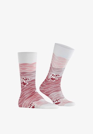 Paar weiße Socken mit roten, wellenförmigen Linienmustern und kleinen roten Illustrationen eines Strandsonnenschirms, der Sonne und einer liegenden Person.