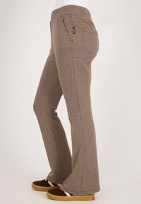 Hondstooth-gepatrooneerde flared broek in bruin en room met een elastische tailleband en zijzakken, gemaakt van een stof met een gladde textuur.