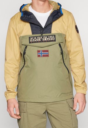 Mand iført en khaki- og tanfarvet hættejakke med frontlomme, Napapijri-logo og norsk flagpatch.