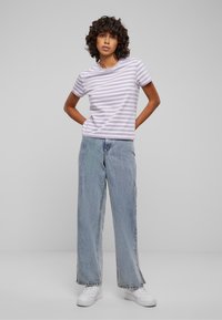 Stripet lavendelfarget T-skjorte med rund hals, kombinert med lysebl�å vide jeans og hvite joggesko. Glatt stoff og avslappet passform.