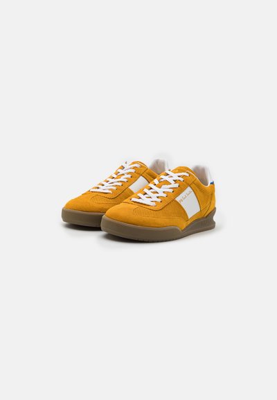 Yellow suede sneakers with white accents, featuring a textured design, round toe, and beige rubber sole, laced with white shoelaces.