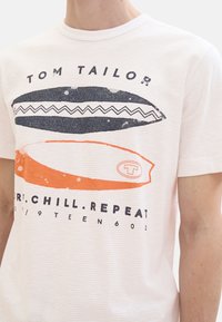 Camiseta de manga corta blanca con un gráfico de tabla de surf en azul marino y naranja, textura a rayas, y el texto "TOM TAILOR" y "SURF.CHILL.REPEAT."