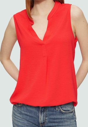 Red sleeveless top with a V-neck and a relaxed fit. Made from a lightweight, textured fabric. Paired with high-waisted denim shorts.