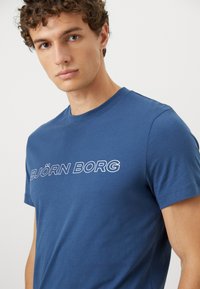 Μπλε βαμβακερό t-shirt με στρογγυλή λαιμόκοψη και κοντά μανίκια, με το "BJÖRN BORG" τυπωμένο σε λευκό στο στήθος. Απαλή υφή.