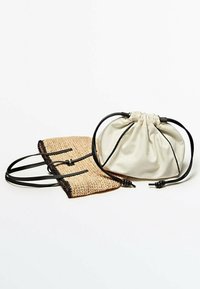 Pochette en tissu beige avec cordons de serrage noirs à côté d'un sac en paille tressée avec une bordure noire et deux anses noires, tous deux compacts et à la texture douce.