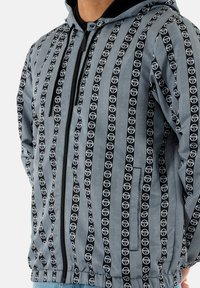 Chaqueta con capucha en azul claro con patrón de logotipo negro, que cuenta con cierre de cremallera, textura de espiga y cintura elástica para un mejor ajuste.