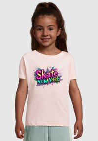 Lyserød bomulds t-shirt med et farverigt grafisk design med teksten "Skate New York" og splatter accenter i livlige farver.