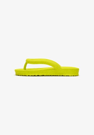 Sandalia tipo flip-flop de espuma de color amarillo brillante con suela gruesa y tira ancha, mostrada de lado sobre un fondo blanco.