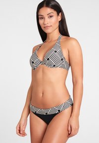 Black and white striped bikini featuring a halter top and low-rise bottom, with a textured band at the waist. Smooth fabric construction.