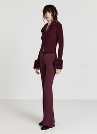 Bordeauxfarbener Pullover mit einem Kragen und Manschetten aus Kunstpelz, gerippte Textur; kombiniert mit passenden enganliegenden Hosen, die eine schlanke Silhouette schaffen.