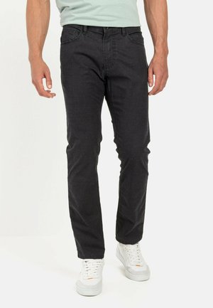 Black jeans with a slim fit, five-pocket design, and a smooth texture. Paired with white sneakers for contrast.