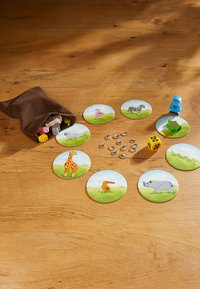 Colorful animal-themed game pieces, circular cards with illustrations, a brown fabric bag, wooden dice, and clear tokens on a wooden surface.