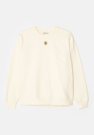 Cream-colored sweatshirt with round neckline, long sleeves, and ribbed cuffs. Features a small embroidered logo on the chest. Soft texture.