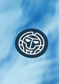 Tela azul claro con una textura suave que presenta un logotipo circular azul marino que representa un rostro estilizado en líneas blancas.