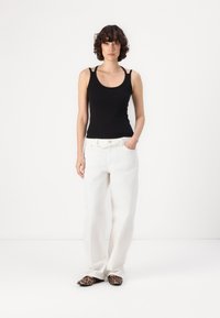 Black sleeveless top, white wide-leg pants, and leopard print shoes. Soft fabric; fitted top with thin straps and loose-fitting trousers.