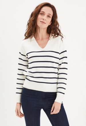 Pull col en V blanc avec des rayures horizontales bleues marine, fabriqué en tissu tricoté. Les manches longues et l'Hem côtelé complètent le design.