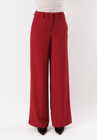 Pantaloni a gamba larga in un ricco tessuto rosso, caratterizzati da una texture liscia, una vestibilità sartoriale e un dettaglio piegato davanti. Completati da una vita e passanti per cintura.