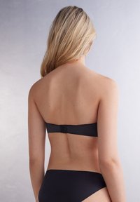 Sort strapless bikini-top med en sikker lukning bagpå og en glat overflade, parret med matchende bikini-bund. Simpelt og minimalistisk design.
