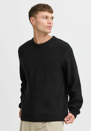 Black knitted sweater with a ribbed texture, crew neckline, and long sleeves. The fit is slightly loose, with a straight hemline.