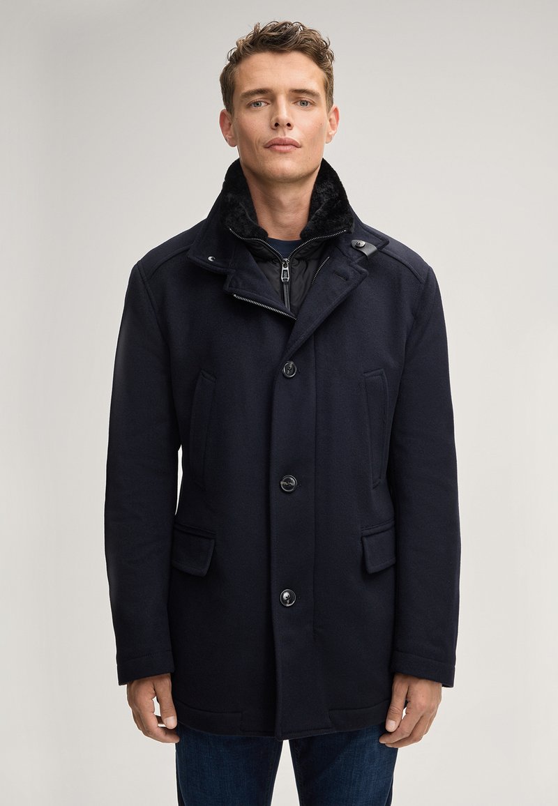 Cappotto in misto lana color navy con colletto testurizzato, quattro tasche frontali, chiusura con bottoni e strato interno con zip.