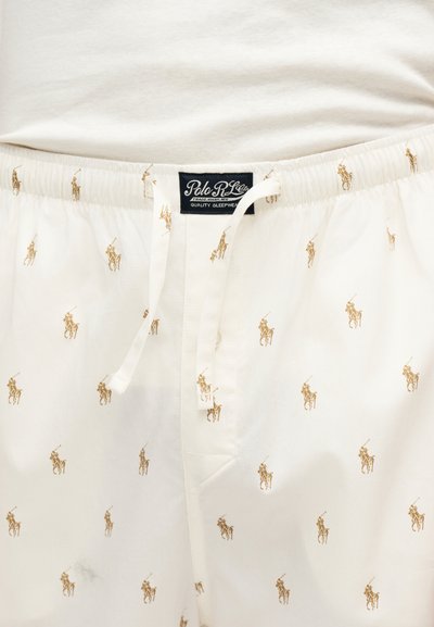 Pantalon de nuit blanc avec logos joueurs de polo couleur beige, taille élastique avec cordon blanc, et étiquette Polo Ralph Lauren au centre devant.