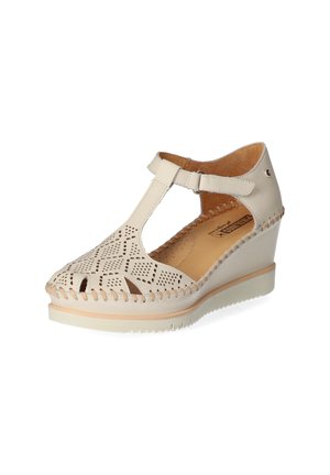 Beige wedge sandals feature perforated leather, an open toe, ankle strap with buckle, and woven detailing around the sole.