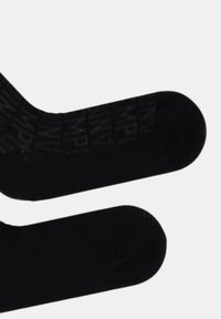 Par sorte crew-sokker, den ene med et tonalt gentagende mønster af teksten "WPL" og "AIPP", lagt fladt på en hvid baggrund.