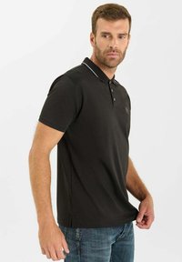 Zwarte polo met korte mouwen en een kraag met twee knopen, voorzien van witte accentstiksel langs de hals en een klein logo op de borst.