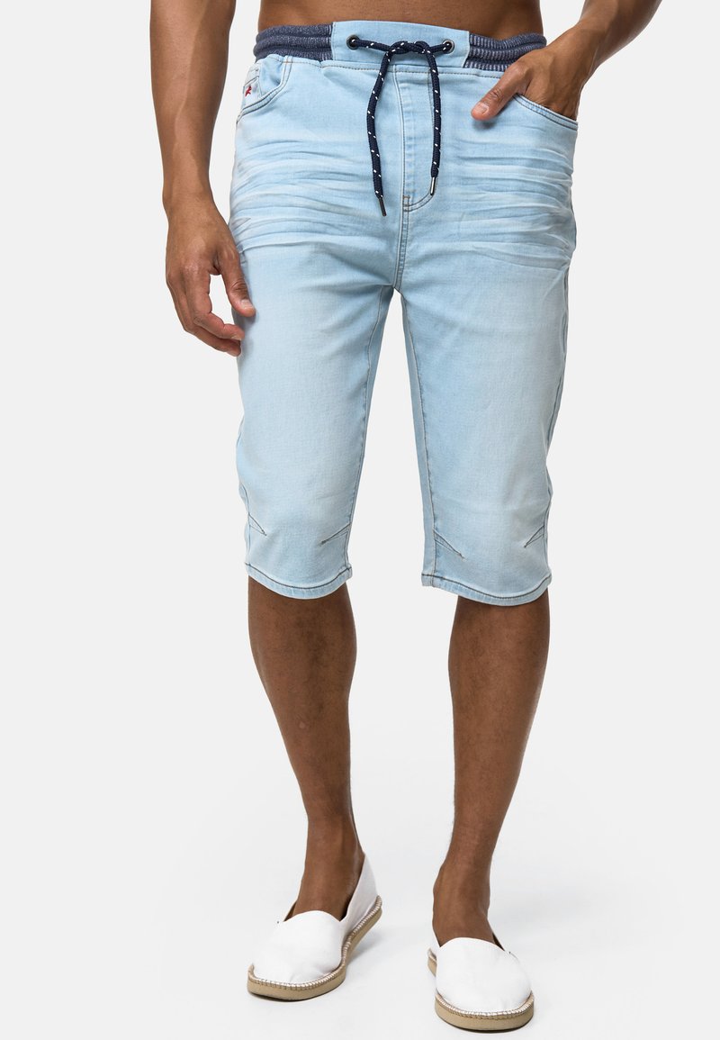 Shorts de mezclilla azul claro con cintura con cordón, dos bolsillos frontales y detalles de costura sutiles en el dobladillo. Diseño casual y de largo hasta la rodilla.