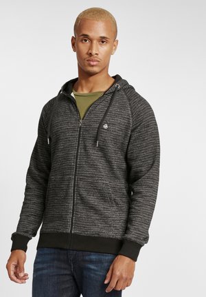 Black and gray zip-up hoodie with a textured fabric, drawstring hood, front pockets, and ribbed cuffs, worn over a green shirt.