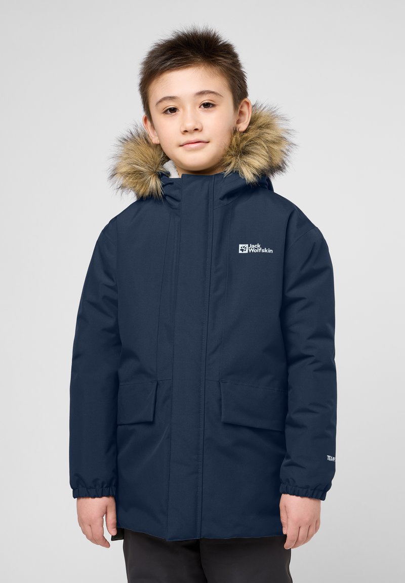 Tmavě modrá parka s kapucí lemovanou kožešinou, dvěma předními kapsami, elastickými manžetami a logem na levé hrudi, navržena pro teplo a pohodlí.