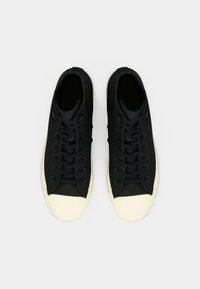 Sneaker alte in tela nera con punta in gomma bianca e suola testurizzata. Presentano lacci neri e fori di ventilazione sui lati.