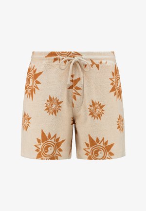 Pantaloni corti beige in pile con un motivo a sole e yin-yang in arancione ruggine. Vita elastica con cordino, texture morbida e lunghezza a metà coscia.