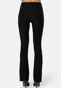 Zwarte uitlopende broek met een gladde textuur, medium hoge taille en twee achterzakken. Het ontwerp heeft een aansluitende silhouet tot de uitlopende zoom.