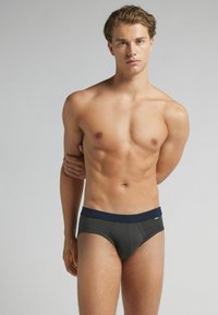 Donkergrijze korte onderbroek met een marineblauwe tailleband. De stof lijkt glad en rekbaar, ontworpen voor een aansluitende pasvorm.