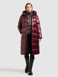 Pikk bordoopunane sulejope kapuutsiga, millel on läikiv tekstuur ja küljetaskud. Kandmise all on varrukateta, tuftitud aluskiht ning mustad saapad.