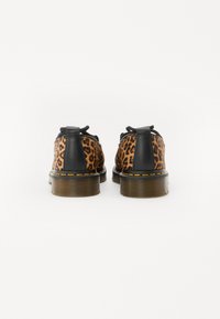 Scarpe nere in pelle con retro a stampa leopardata, punta tonda e suola spessa marrone, caratteristiche di cuciture arancioni lungo il bordo.