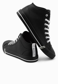 Svarta högskurna sneakers i syntetmaterial. Vita snören och ränder vid sulan. Har en märkeslogotyp på hälen och en texturerad yta.