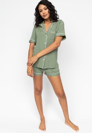 Groene pyjama-set met korte mouwen, bestaande uit een knoopshirt met een borstzak en bijpassende shorts, beide met witte biezen. Zacht, lichtgewicht stof.